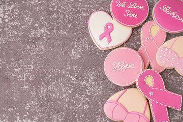 Cookies with pink ribbons and supportive words on grey grunge background. Breast cancer awareness...