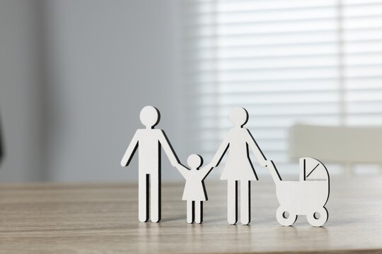 Family law. Figure of parents with children on light wooden table