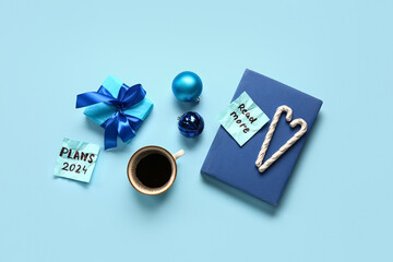 Sticky notes with goals for 2024, gift box, cup of coffee and Christmas decorations on blue background - obrazy, fototapety, plakaty