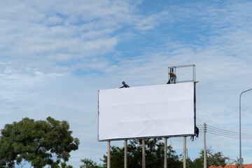 Worker prepares billboard to installing new advertisement. Industrial climber working on a ladder - placing an advertising banner.