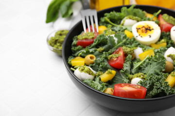 Delicious salad with pesto sauce on white tiled table, closeup. Space for text