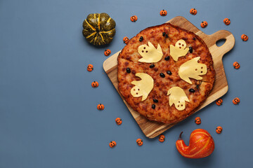 Wooden board with tasty pizza and pumpkins for Halloween party on blue background