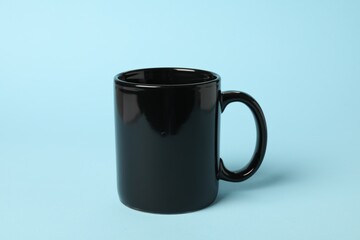 One black ceramic mug on light blue background