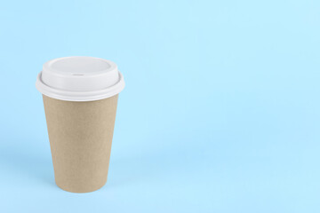 Paper cup with plastic lid on light blue background, space for text. Coffee to go