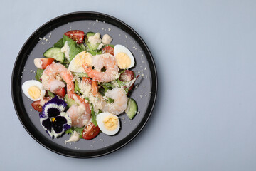 Delicious Caesar salad with shrimps on grey background, top view. Space for text