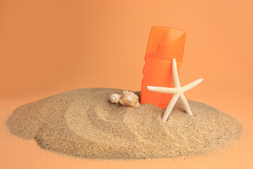 Sand with bottle of sunscreen, starfish and seashells against orange background. Sun protection