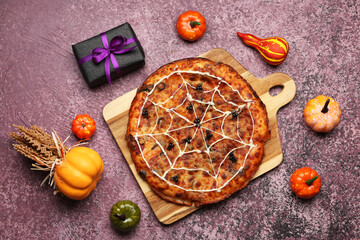 Wooden board with tasty pizza and decorations for Halloween party on purple background