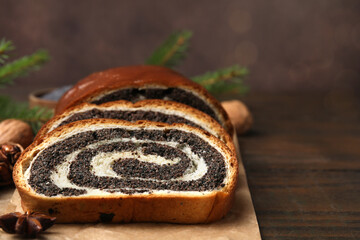 Slices of poppy seed roll and anise star on wooden table, closeup with space for text. Tasty cake