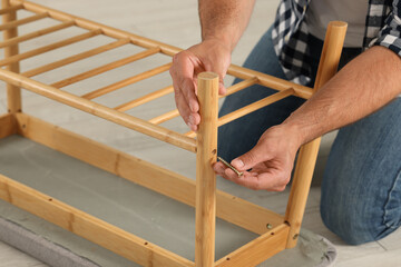 Man with self-tapping screw assembling furniture on floor, closeup