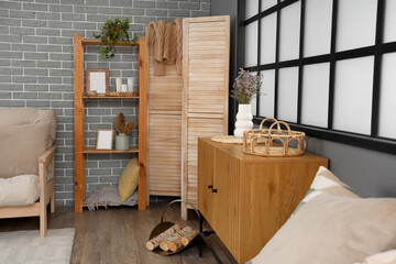 Interior of light living room with shelf unit and folding screen