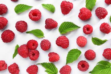 Tasty ripe raspberries and green leaves on white background, flat lay - obrazy, fototapety, plakaty