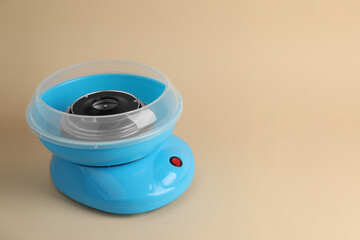 Portable candy cotton machine on beige background, space for text