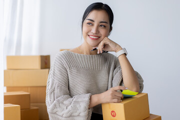 Startup happy Asian woman business owner works with a box at home, prepare parcel delivery SME...