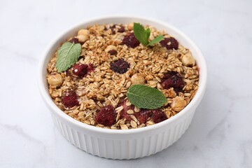 Tasty baked oatmeal with berries and nuts on white marble table, closeup