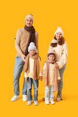 Happy family in winter clothes on yellow background