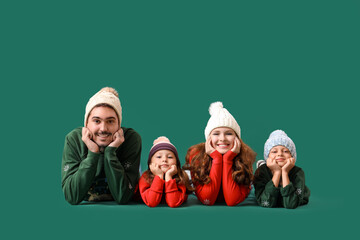 Happy family in warm sweaters lying on green background