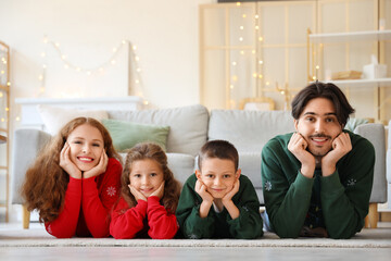 Happy family in warm sweaters lying on floor at home