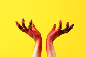 Bloodstained zombie hands on yellow background. Halloween celebration