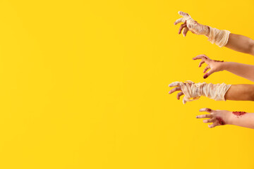Zombie and mummy hands on yellow background. Halloween celebration