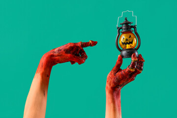 Bloodstained zombie hands with Halloween lantern on green background
