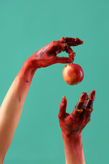 Bloodstained zombie hands with apple on green background. Halloween celebration