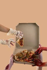 Zombie and mummy hands holding box with pizza on beige background. Halloween celebration