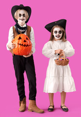 Little children dressed for Halloween with candies and pumpkin on purple background