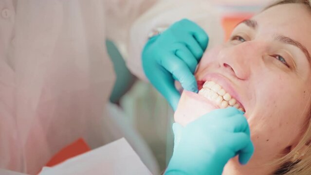 Dental orthodontist installs invisible transparent aligners to woman.