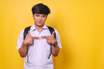 Young Asian schoolboy wearing backpack and uniform showing shy and doubt gesture playing nervously...