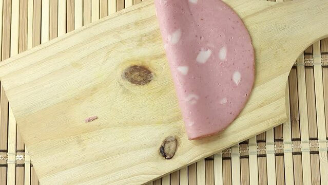Slices of smoked mortadella on wooden cutting board