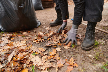 Father-daughter duo bonding in the garden as they work together to collect fallen leaves and fill up a bag on a crisp autumn day.