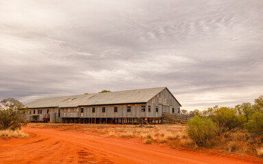 A sheep shearing shed with red dirt and an overcast sky as background in Currawinya National Park...
