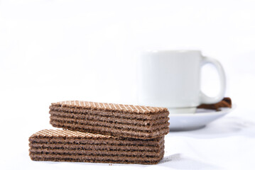 Obraz na płótnie Canvas chocolate wafer cookie with cup of coffee in the background isolated on white background