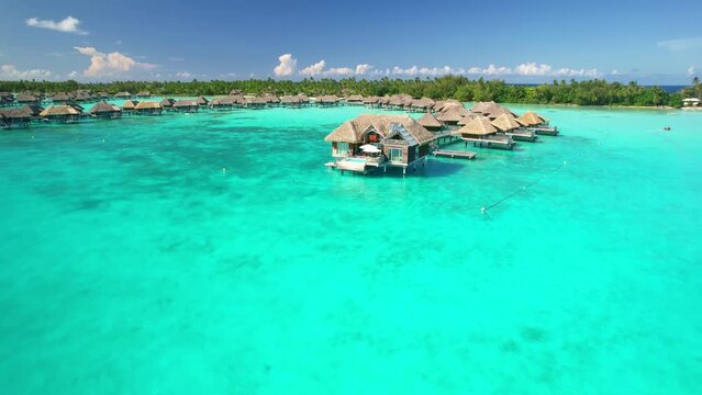 Aerial view of tropical paradise of Bora Bora island, turquoise crystal clear water of scenic blue lagoon, over water bungalows. French Polynesia, Tahiti drone shot. 
