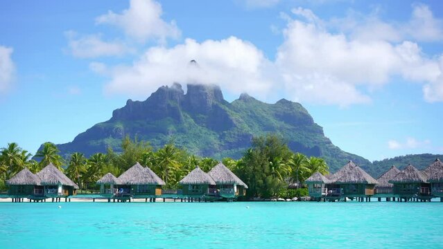 Tahiti. Bora Bora overwater bungalow villas, honeymoon couple in turquoise lagoon. French Polynesia. Luxury vacation, romantic getaway, exotic resort destination.  