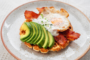 Breakfast waffles, fried eggs, bacon and avocado