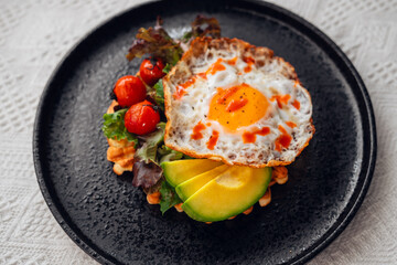 Breakfast waffles, fried eggs, avocado and salad