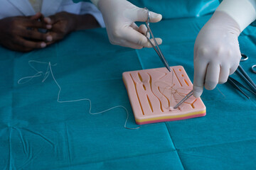 Experts demonstrate how to sew silicone sheets to students of various nationalities, practice stitching on the skin suture silicone pad © chomplearn_2001