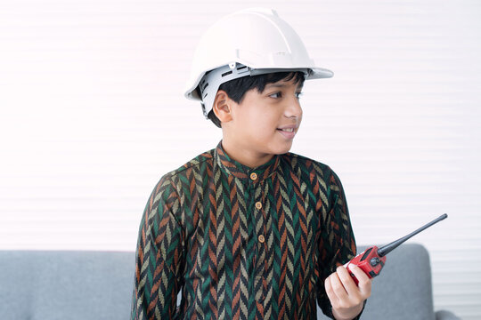 Indian boy wearing traditional clothes, wearing protective helmet and a walkie-talkie, pretending to be an engineer