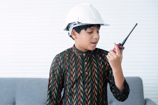 Indian boy wearing traditional clothes, wearing protective helmet and using walkie-talkie, pretending to be an engineer