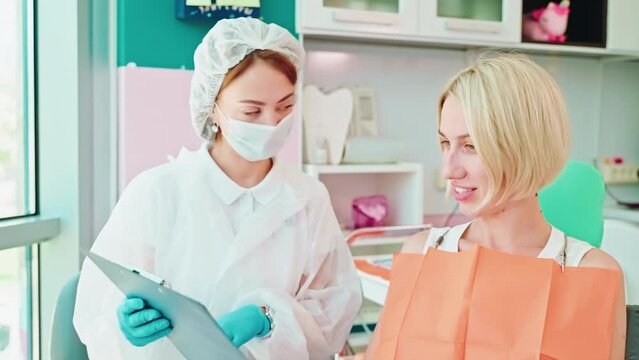 dentist and female patient discussing plan of treatment in medical office, stomatologist appointment