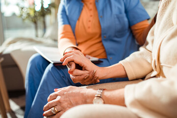 Close up of caregiver holding a hand of her senior patient at home