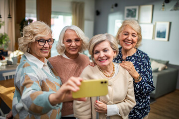 Group of senior friends taking a selfie on a smartphone at home