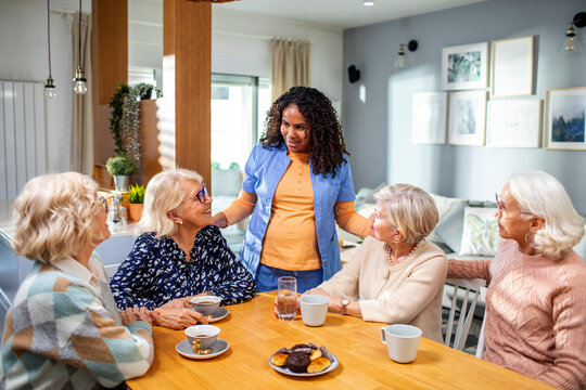 Senior group of female friends consulting their caregiver at home