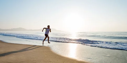 Zelfklevend Fotobehang Young man running along beach  in the morning © xy