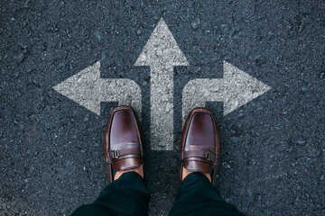 Businessman standing on road with three direction arrow choices, Correct pathway between left, right and front, Decision concept.