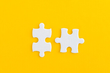 Obraz premium Two puzzle pieces on yellow background