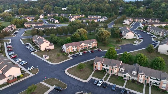 American neighborhood of apartment complexes in suburbs. Aerial reveal of many houses, homes, and duplexes next to rural fields.