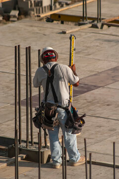 Construction worker measuring rebar at a construction site