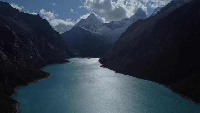 Camera slowly rising up while looking over Laguna Paron to the snow covered mountain peaks in the distance